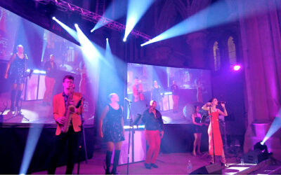 Gorton Monastery Stage lighting and projectors with live band performing, they are dressed in red and black